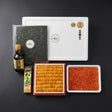 Sushi ingredients including rice, fish roe, bafun uni, nori, and a bottle on a dark background